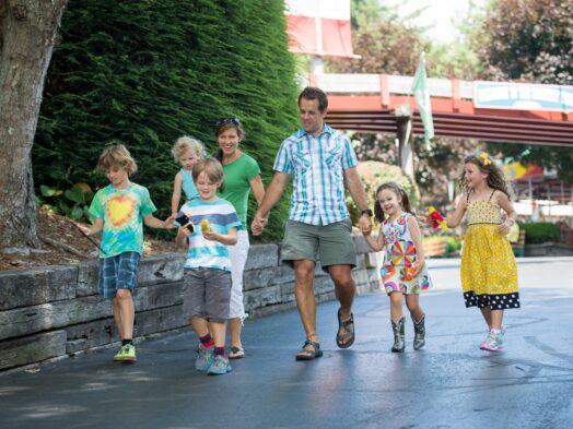 A family of five children and two parents walking down a pathway at Tweetsie Railroad